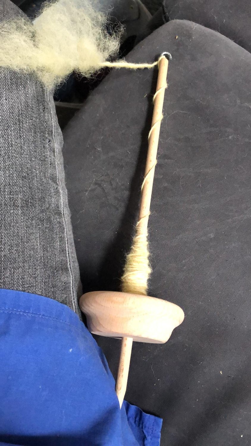 Wolle wird mit einer Handspindel versponnen